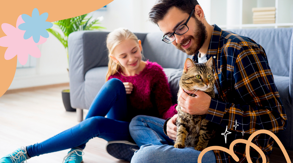 Joyful dad and daughter smiling and holding their beloved cat.